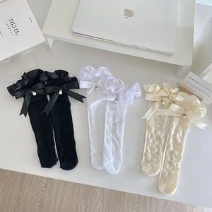 Détail des chaussettes en dentelle à cœurs avec nœuds en satin et perles élégantes