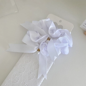 Détail de chaussettes en dentelle blanche avec cœurs ajourés et nœuds en satin