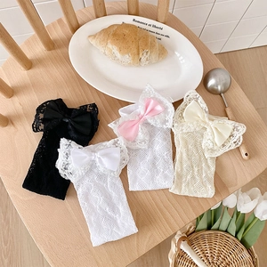 Pack of four girls lace mesh knee high socks with large satin bows on wooden seat