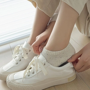 Close-up of white platform sneakers paired with beige speckled knit low-cut socks