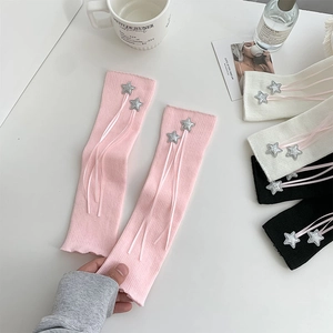 Detail of knit leg warmers with silver stars and pink ribbons in a cozy setting