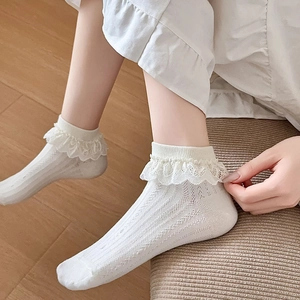 Détail de chaussettes blanches Lolita avec maille ajourée et volants en dentelle