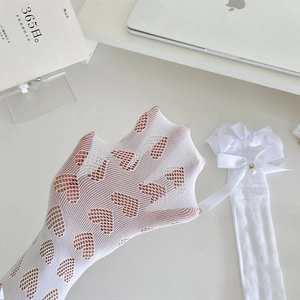 Détail de chaussettes blanches résille à cœurs avec nœuds et pendentifs perles