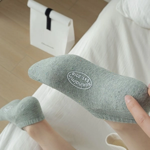 Close-up of light green flecked cotton socks featuring embroidered logo and ribbed cuffs