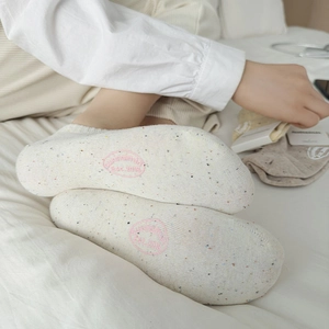 Detail of speckled cotton ankle sock showing pink circular logo and nonslip sole grip