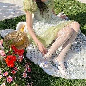 Detailed white lace tights featuring side heart patterns and delicate ankle bows outdoors