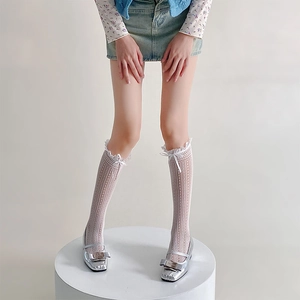 Detail of white lace mesh knee high socks with bow tie and silver Mary Jane shoes