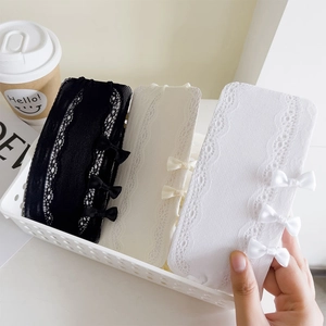 Detailed lace pattern with silk bows on mesh stockings in black, cream, and white