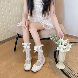 Détail de chaussettes résille à cœur blanc avec bords à volants, nœuds et Mary Janes
