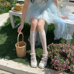 Vue détaillée des bas Lolita en dentelle blanche avec de délicats nœuds en ruban bleu clair