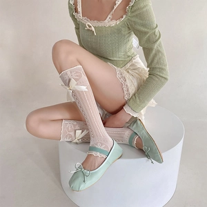 Détail de chaussettes hautes blanches en dentelle avec nœud en soie et perles sur le côté