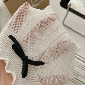 Détail de chaussettes en dentelle blanche avec nœud noir et bordure à volants