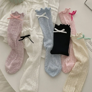 Détail de chaussettes en maille ajourée avec bords à volants et nœuds en satin colorés
