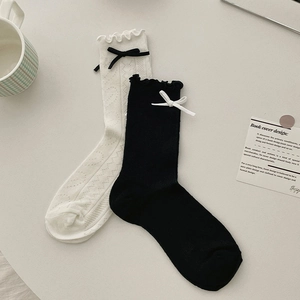 Détail de poignets à volants et nœuds contrastés sur des chaussettes en maille ajourée