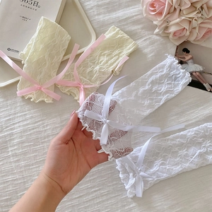 Detailed macro of lace leg warmers with bows on a rustic soft white fabric background