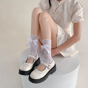 Détail de chaussettes blanches en dentelle avec nœud et perles avec Mary Janes à plateforme
