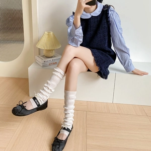 Detailed close-up of white ruffled leg warmers featuring a delicate bow and layered design