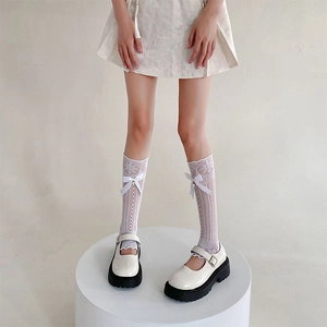 Détail de jambières en résille blanche avec nœuds et chaussures Mary Jane à plateformes