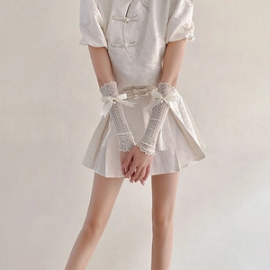 Close-up of white lace arm sleeves with mesh detail, delicate bow and pearl pendants
