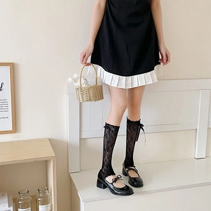 Detail of black lace mesh socks with bow on calf, styled with Mary Jane shoes and dress
