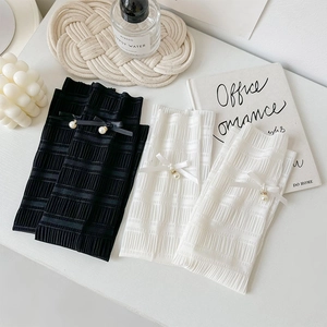 Detail of ruffled knit leg warmers with delicate silk bows and pearl pendant accents