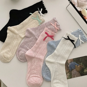 Détail de chaussettes en maille ajourée avec bord à volants et petit nœud délicat