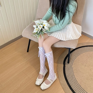 Detail of white lace mesh leg warmers with bow accents and matching Mary Jane shoes