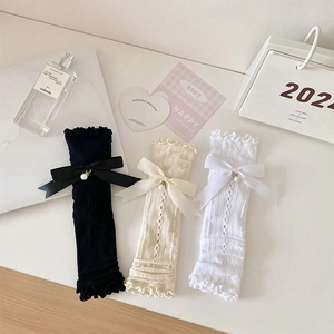 Lace-up leg warmers with silk bows and pearl charms in black, cream, and white
