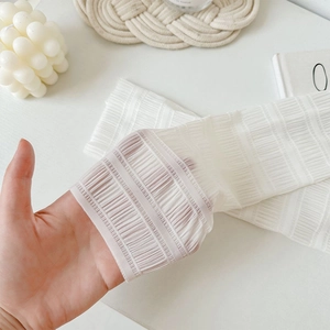 Close-up of white sheer ballet-style arm sleeves showing pleated texture and stretch