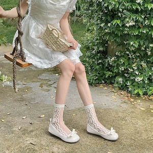 Detail of white floral lace sheer socks with bow flat shoes on an outdoor swing