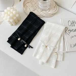 Detail of ruffled arm sleeves featuring delicate ribbon bows and pearl pendants