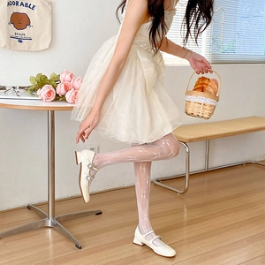 Détail de chaussures Mary Jane blanches avec boucles strass et collants en dentelle à nœuds