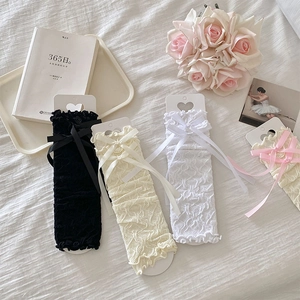 Close-up of lace leg warmers with bows in black beige white and pink colors