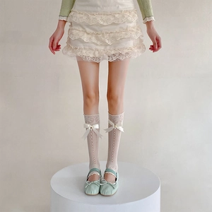 Détail de jambières en dentelle blanche avec nœuds et perles avec ballerines