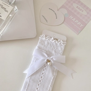 Close-up of white lace sleeve with ribbon bow and faux pearl pendant detail