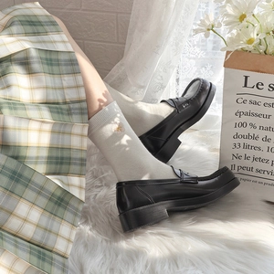 Detail of white embroidered flower socks paired with black loafers and a plaid skirt