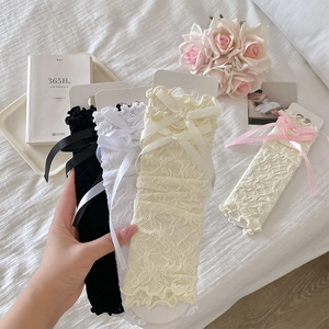 Detail of delicate lace leg warmers with satin bows in sweet Lolita style aesthetic