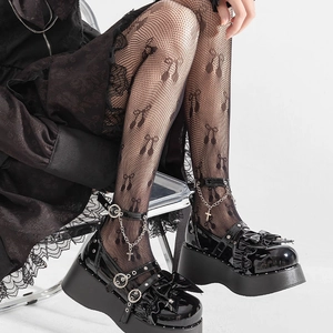 Gros plan de chaussures Mary Jane à plateforme noires avec chaînes et collants résille