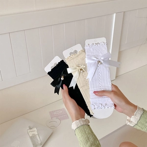 Close-up of lace mesh arm sleeves with ribbon bows and delicate pearl pendants