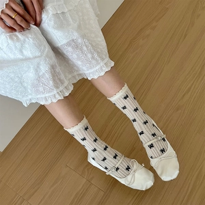 Gros plan de chaussettes blanches à mi-mollet avec nœuds noirs et dentelle