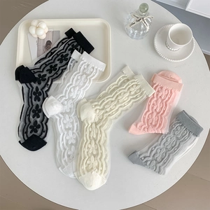 Detail of five floral lace mesh socks in various colors displayed on a white table