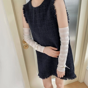Detail of white chiffon leg warmers with delicate bows and pearl accents on tweed dress