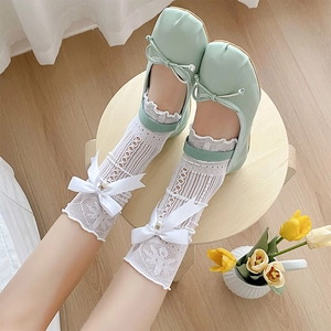 Détail de chaussettes en dentelle blanche avec nœuds en soie et chaussures Mary Jane