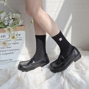 Close-up of black crew socks featuring delicate pink cherry blossom embroidery details