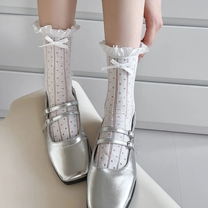 Close-up of white lace socks with ruffled edges, silk bows, and silver Mary Jane shoes