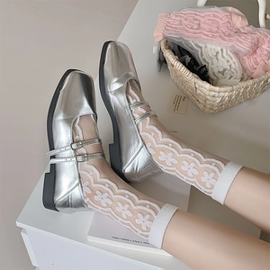 Close-up of silver Mary Jane flats with double straps and floral lace socks