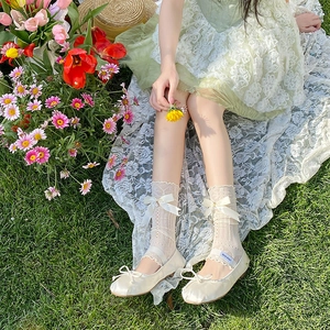 Détail de bas en dentelle à nœuds et ballerines en satin sur fond de fleurs