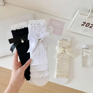 Detail of lace arm sleeves with ruffle edges, silk bows, and decorative pearls