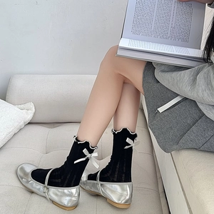 Detail of black rib knit mid-calf socks with silk bows and silver Mary Jane shoes
