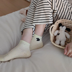 Detail of cream rib-knit ankle sock with colorful dots and black dog embroidery